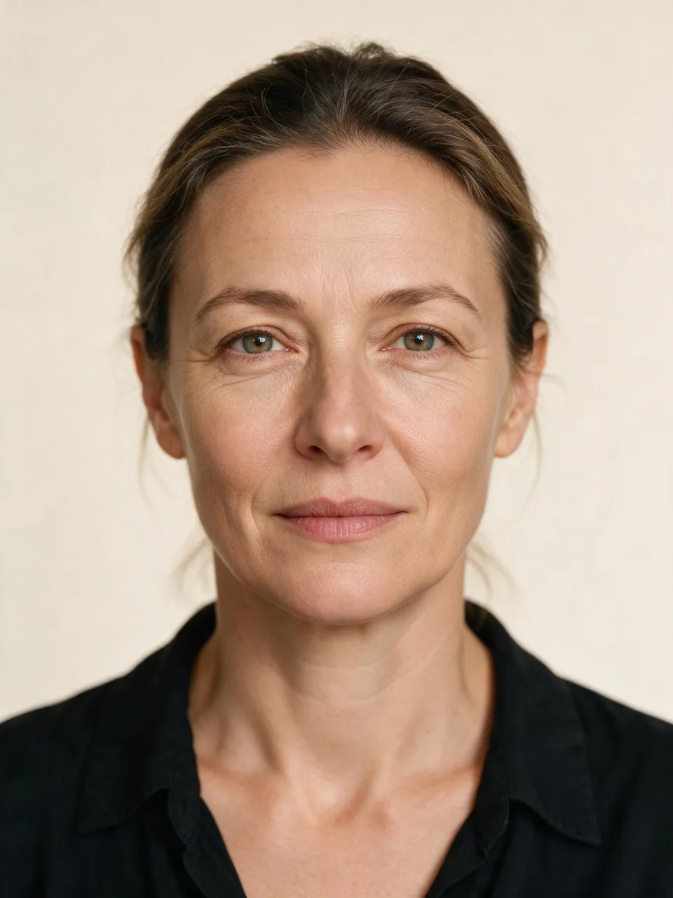 Front-facing studio portrait of a woman in her mid forties with natural, unretouched signs of age.